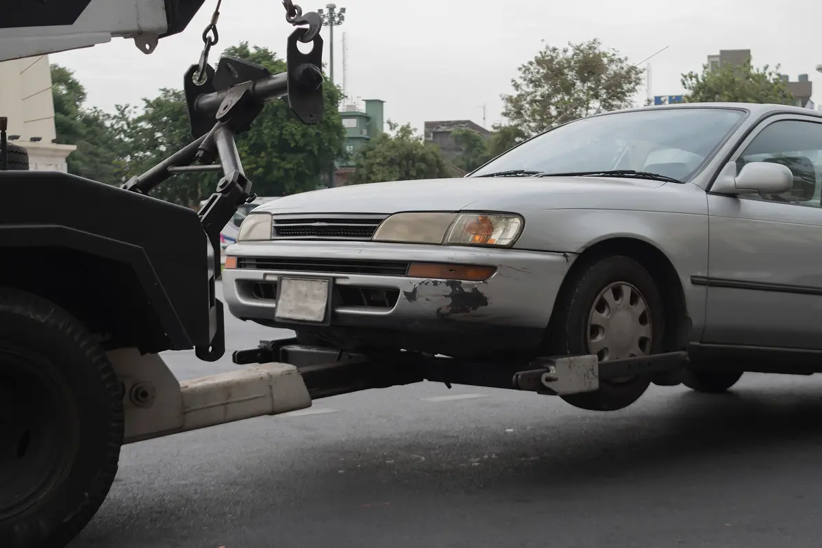 Tow truck lifting a silver car.