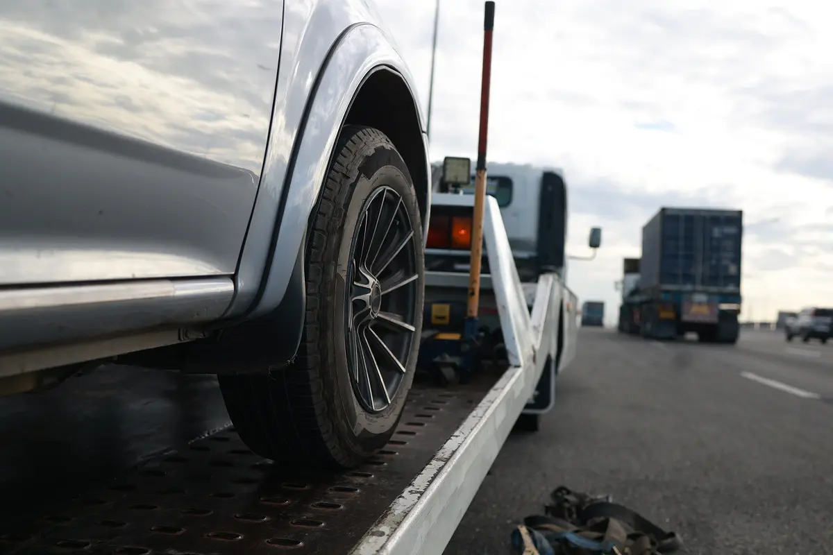 Car being towed on highway roadside.