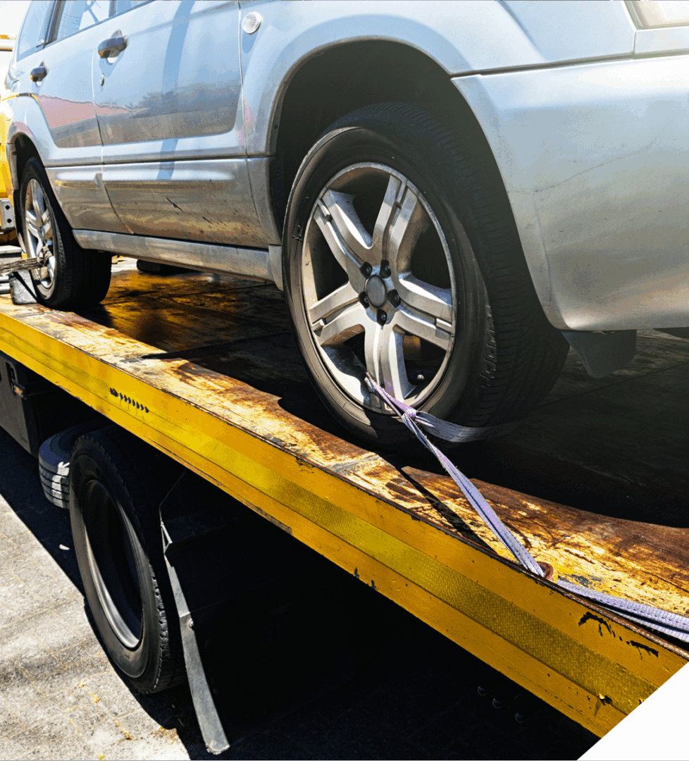 Car secured on yellow tow truck bed.